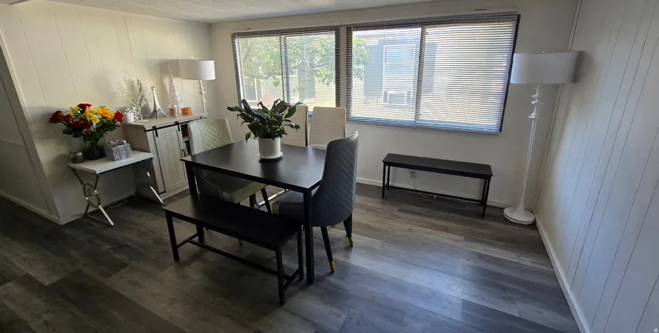 Interior space featuring wood-finish flooring, white paneled walls, and a large window with blinds