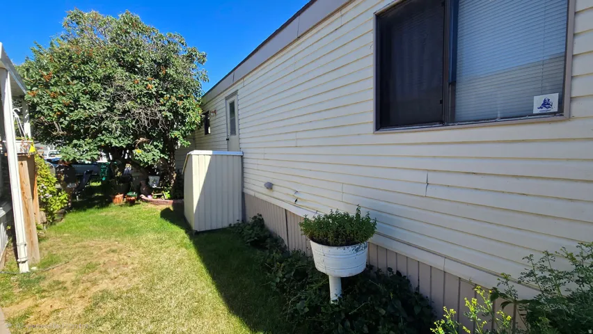 Exterior siding in a light neutral tone featuring a large window with blinds and a screen