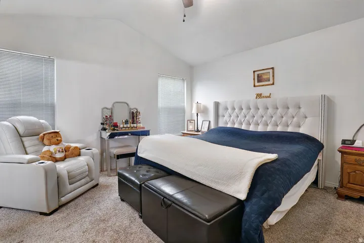 Spacious room featuring vaulted ceilings, light-colored walls, carpeted flooring, and window blinds
