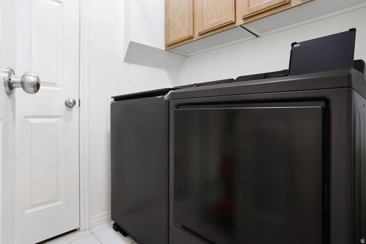 Laundry area featuring white paneled doors, brushed nickel hardware, and wood-finish upper cabinetry