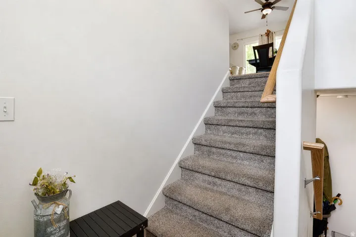 Carpeted staircase with a wood handrail and light-toned walls