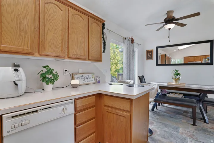 Kitchen with wood cabinetry, light countertops, and a built-in dishwasher