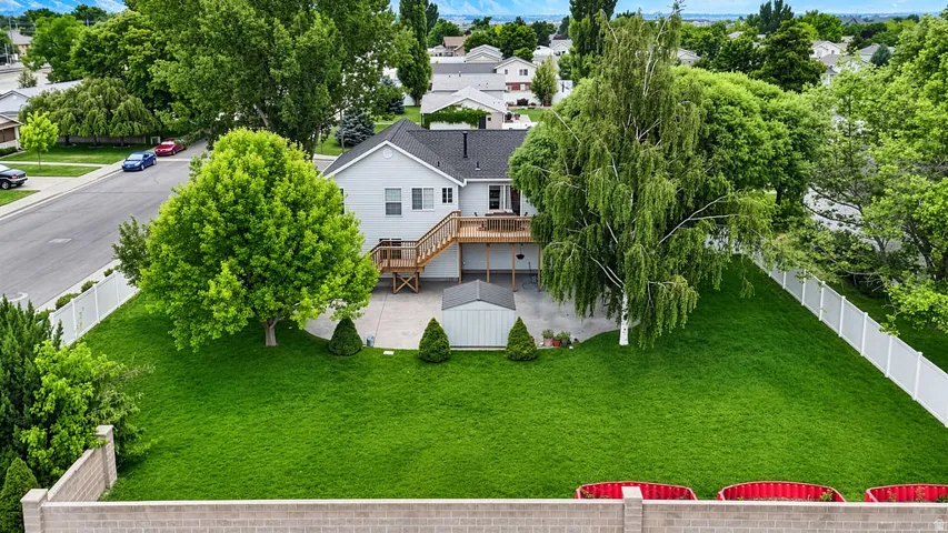 Expansive green lawn with mature trees and a multi-level wood deck