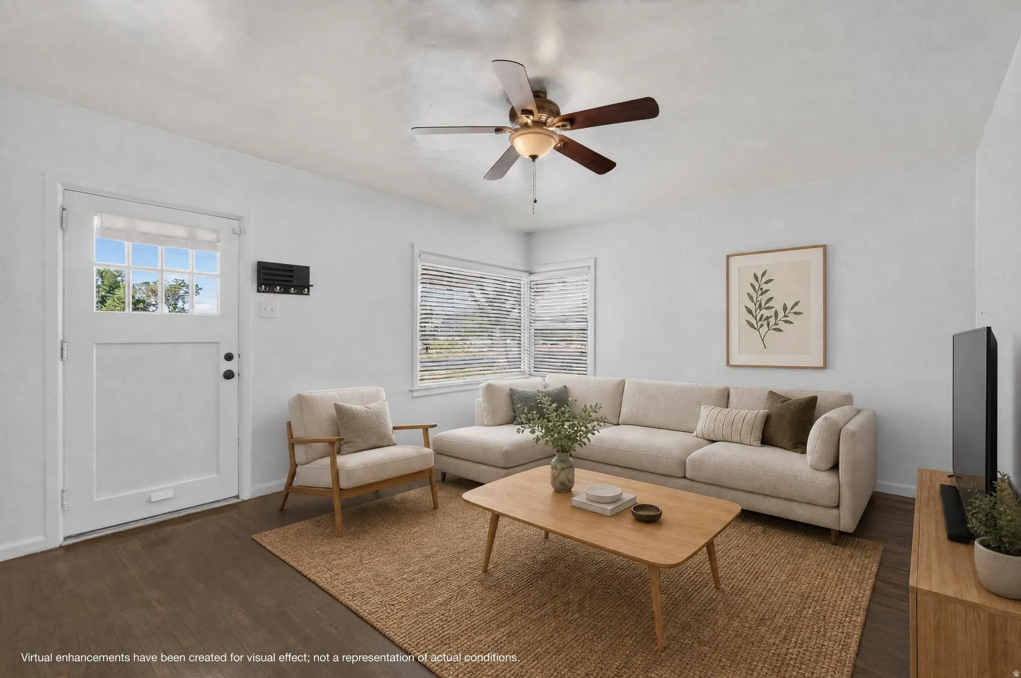 Living area with wood-finish flooring, a ceiling fan with integrated lighting, and multiple windows with blinds