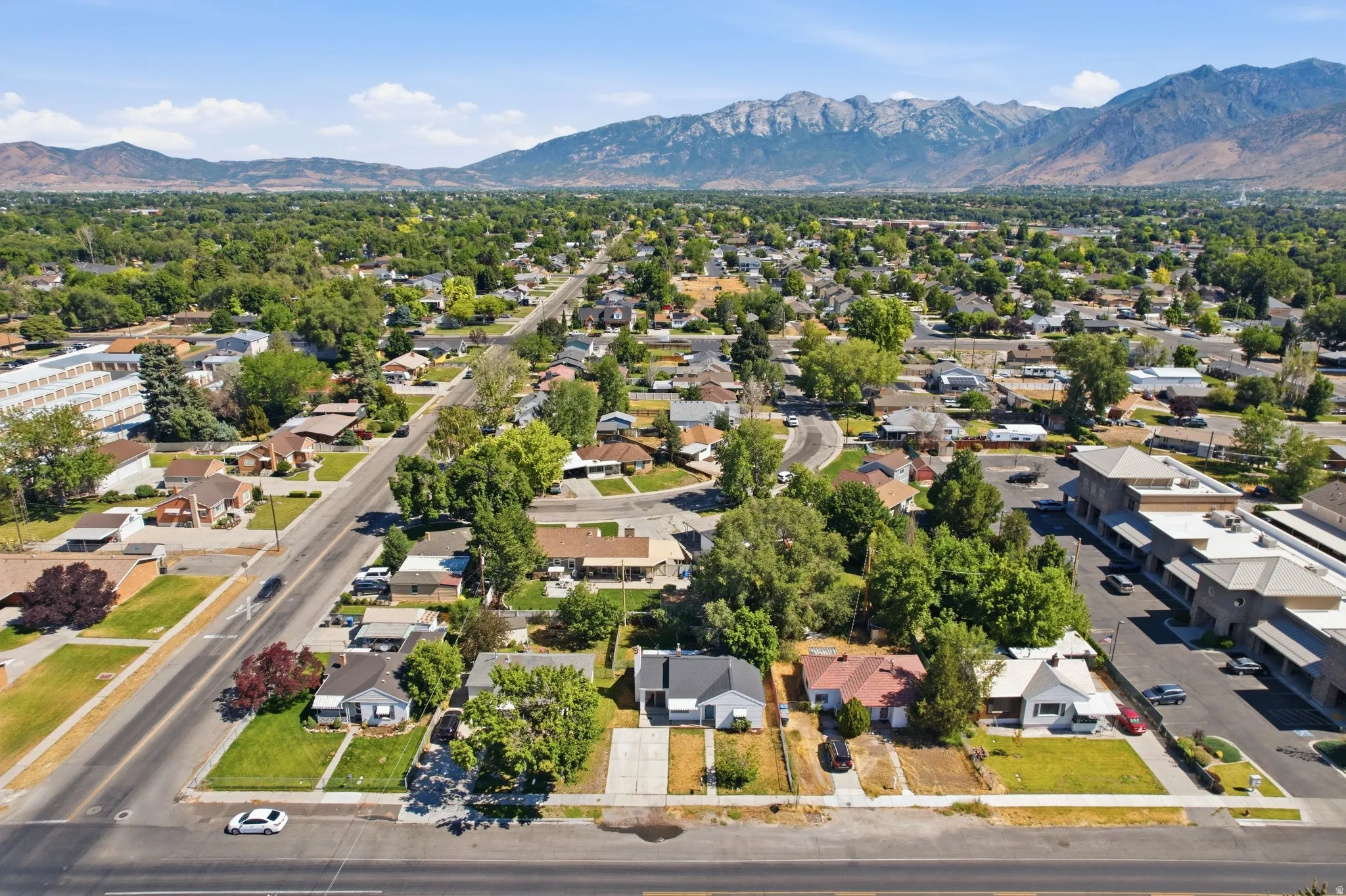 Aerial perspective showcasing a residential area with established trees and mountain backdrop