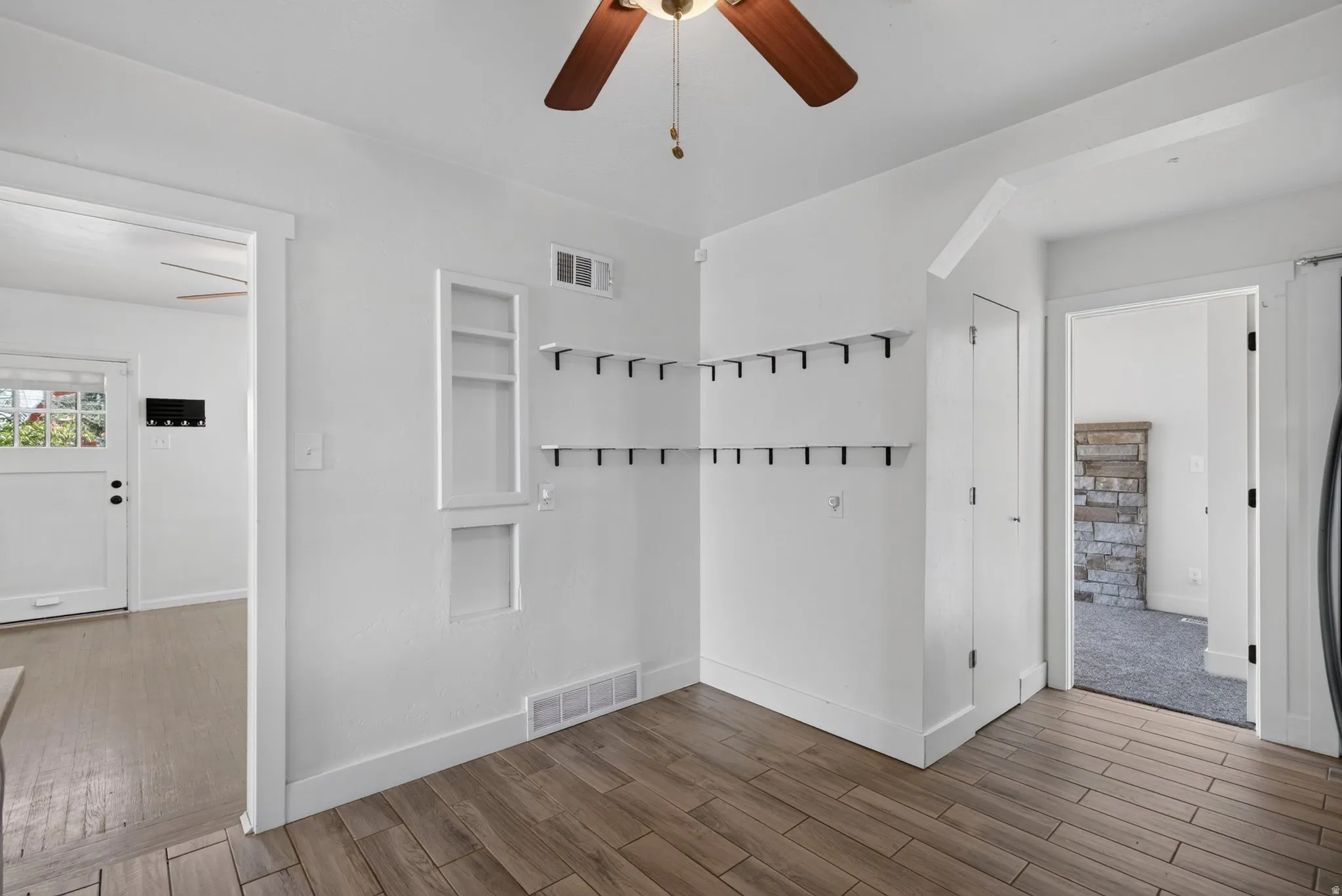 Bright interior space featuring wood-finish flooring, white walls, and a ceiling fan