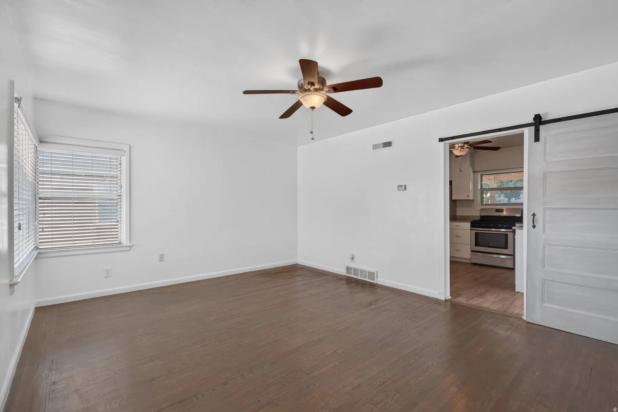 Spacious interior featuring wood-finish flooring, white walls, and a ceiling fan
