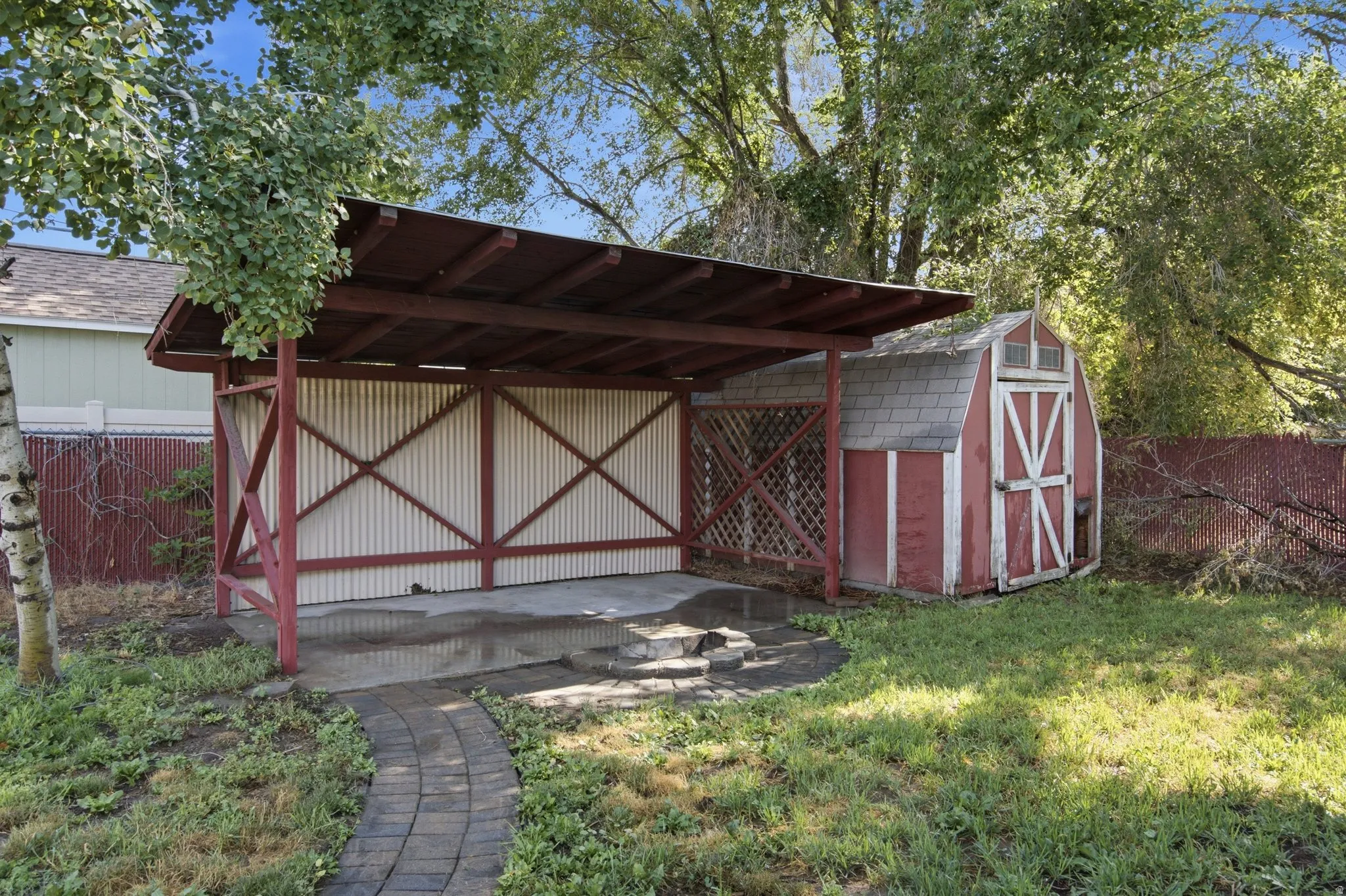 Carport structure featuring a corrugated side panel and a covered concrete pad