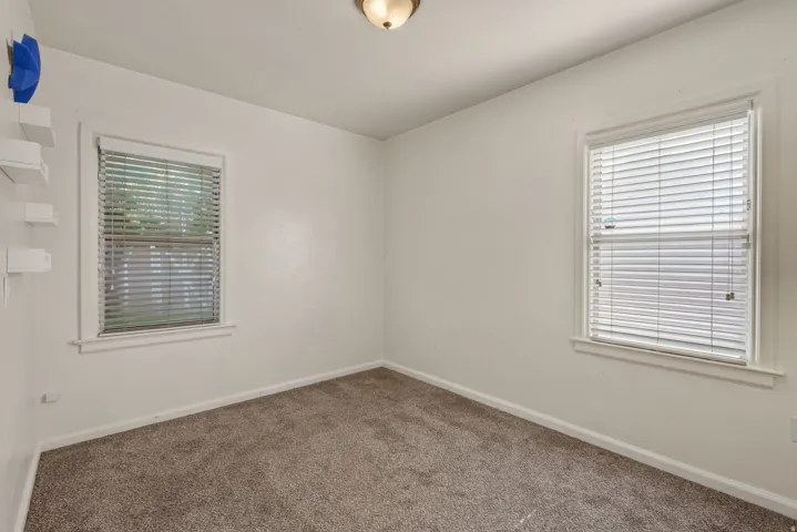 Room featuring two windows with horizontal blinds, neutral wall paint, and carpet flooring