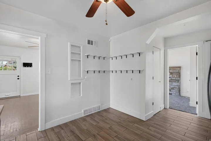Bright interior space featuring wood-finish flooring, white walls, and a ceiling fan
