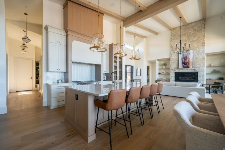 Kitchen featuring a large central island with seating, a range hood with wood-finish trim, and pendant lighting