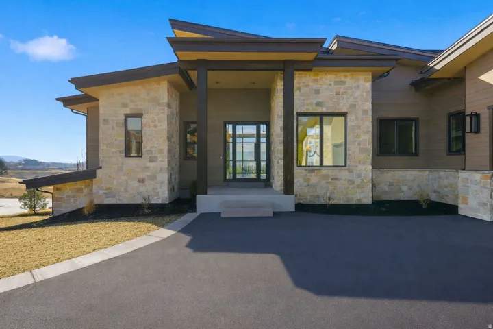 Contemporary exterior with stone cladding and dark horizontal siding, complemented by a covered entry and a paved driveway