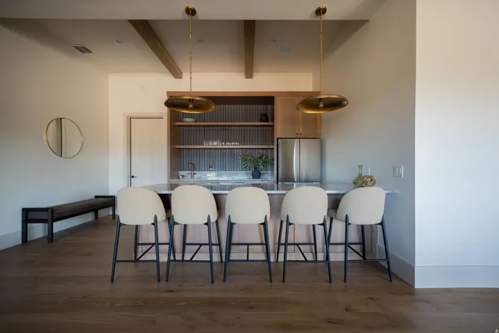 Built-in wet bar featuring a stainless steel refrigerator, wood cabinetry, and a stone countertop