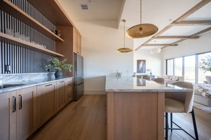 Wood-finish flooring with a multi-functional island, integrated stainless steel refrigeration, and custom built-in cabinetry