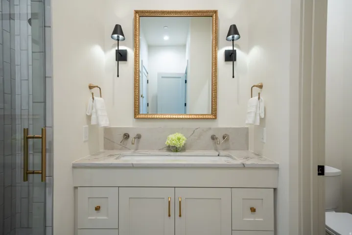 Dual vanity with an integrated rectangular sink, stone countertop, and wall-mounted faucets