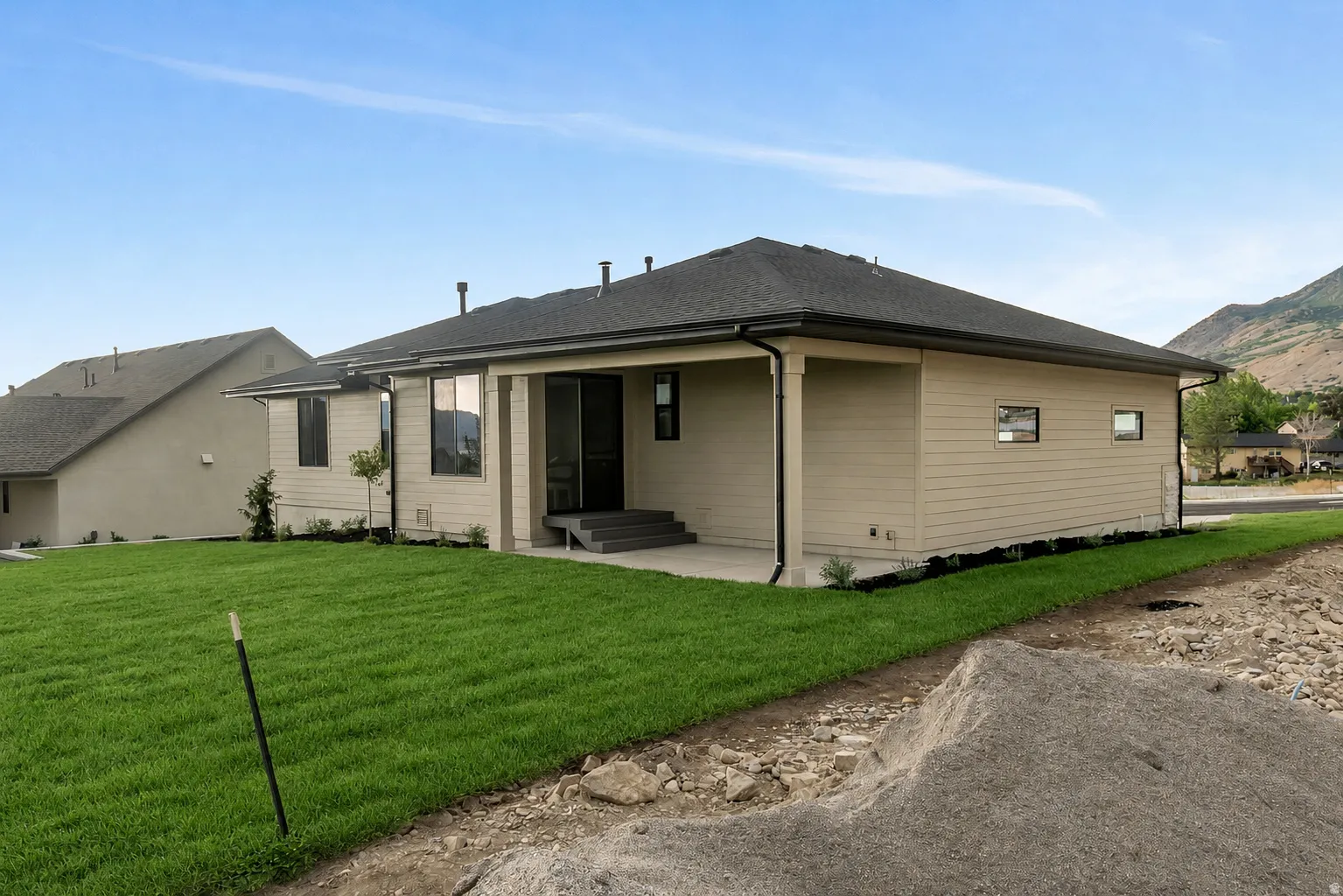 Rear exterior featuring a covered patio, neutral siding, dark shingle roof, and a verdant lawn