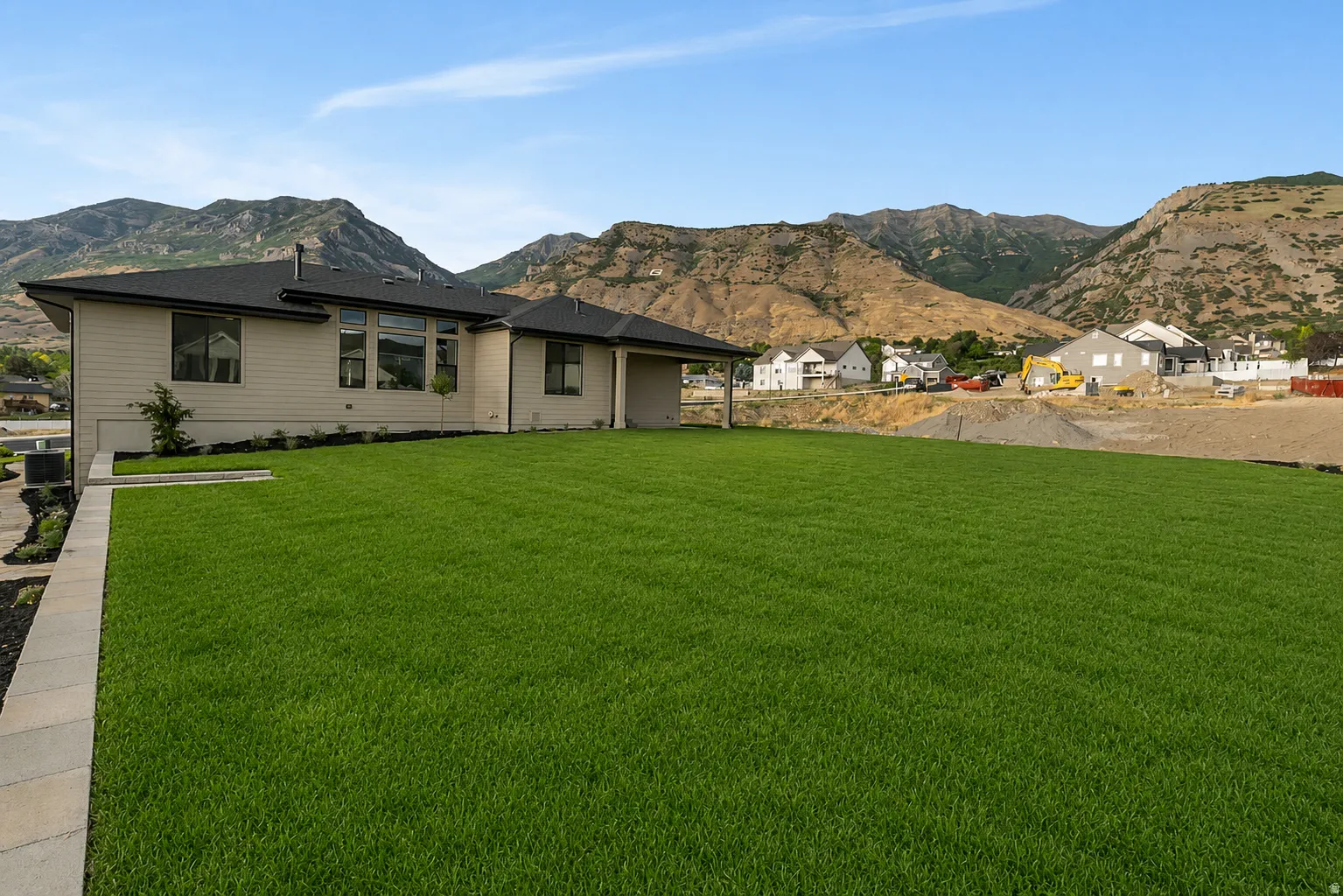 Expansive lawn with a paver border, complementing the residence with light-colored siding and dark roof