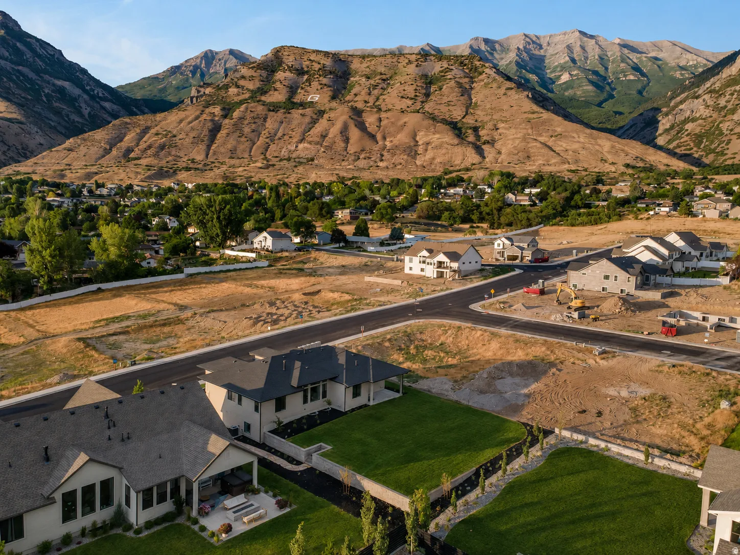 Overhead property view featuring newly constructed residences, undeveloped land, paved roads, and distant mountains
