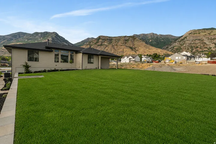 Expansive lawn with a paver border, complementing the residence with light-colored siding and dark roof