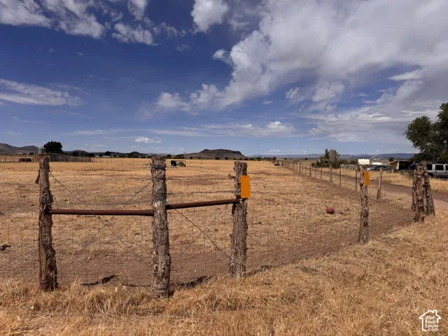 Expansive open land with a rustic wooden fence line and wire fencing