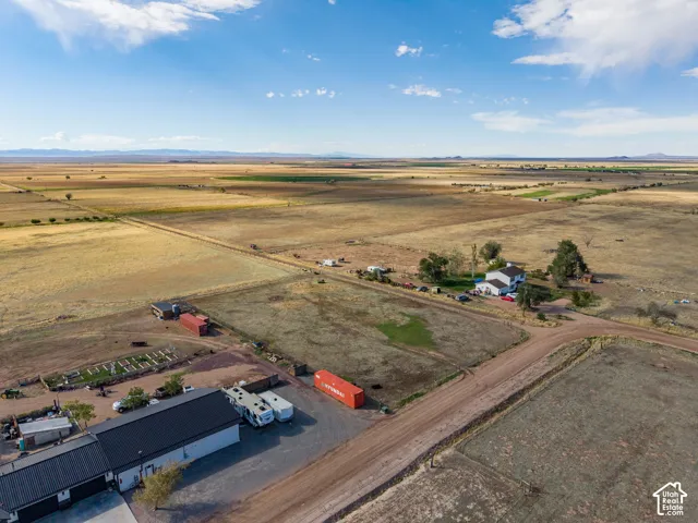 Expansive rural acreage featuring a multi-structure footprint, metal-roofed workshop, dirt road access, and mountain range backdrop