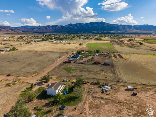 Aerial view featuring expansive acreage, a multi-story residence, and prominent mountain backdrops