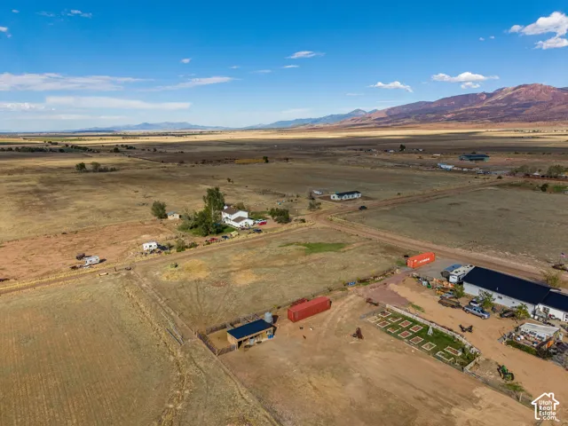 Expansive acreage featuring mountain silhouettes, open plains, a fenced outdoor structure, and integrated planting beds
