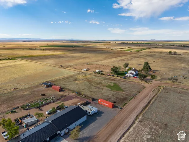 Aerial perspective of expansive rural acreage featuring a multi-building property, detached workshop, and mountain horizon