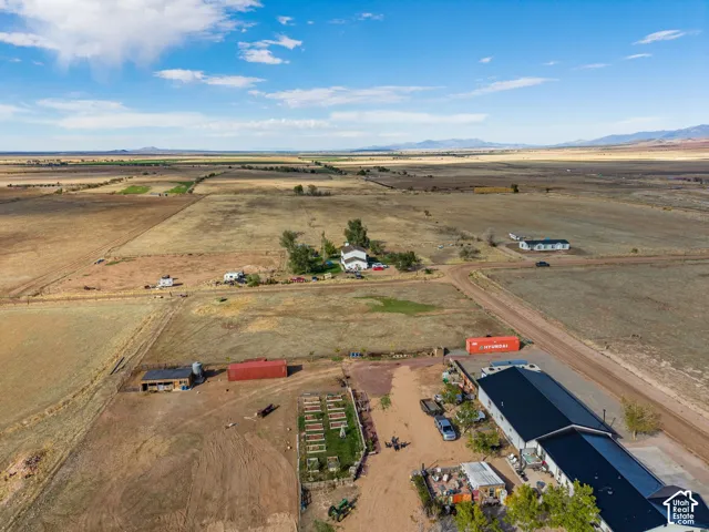 Expansive acreage featuring established garden beds, outbuildings, metal roofing, and distant mountain topography