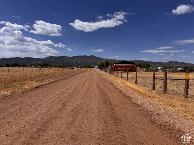 Expansive gravel road providing access to the property, bordered by a rustic wire fence with wooden posts
