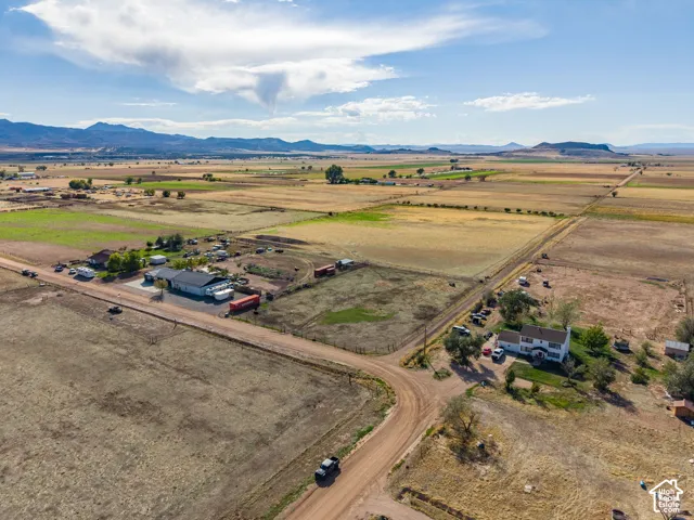 Aerial perspective of a multi-acre property featuring expansive open land, a rural setting, and distant mountain topography