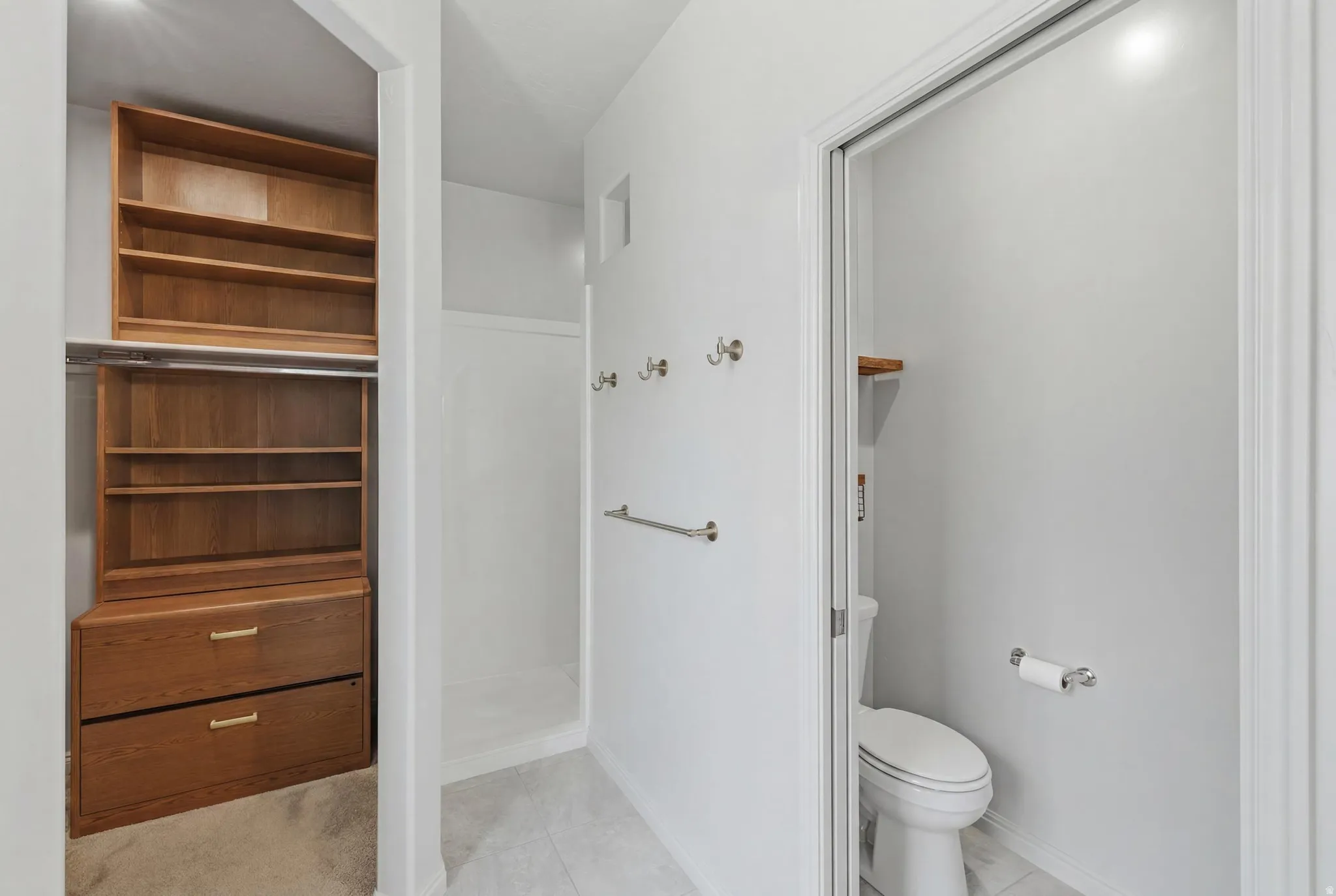 Walk-in closet with built-in shelving and drawers, a shower stall, and a separate toilet area