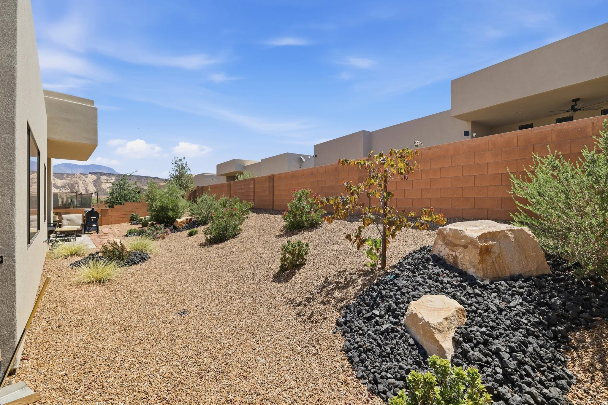 Desert-inspired landscaping featuring a rock garden with natural boulders and black lava rock