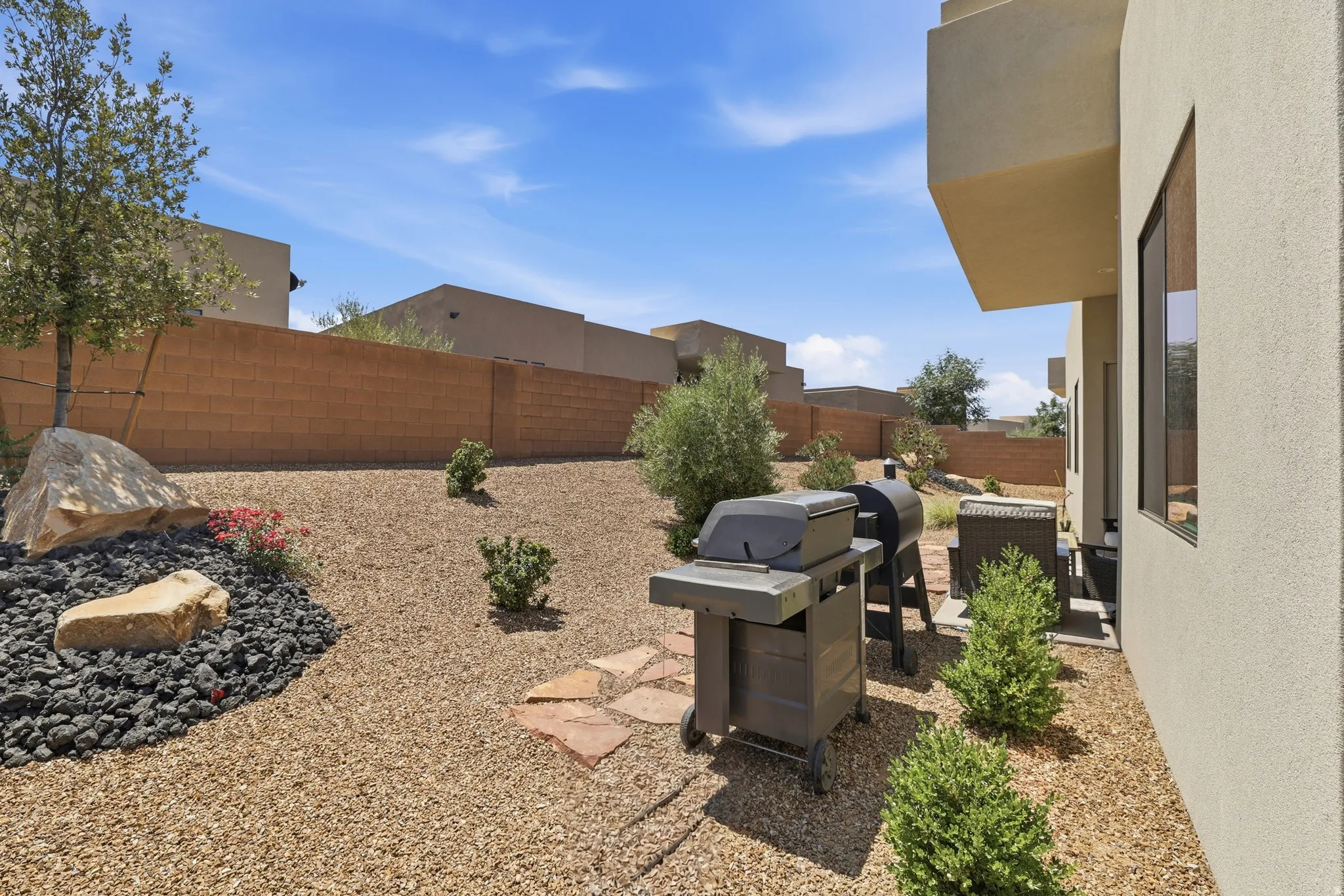 Xeriscape backyard featuring a full-height block fence, natural stone landscaping, and gravel ground cover