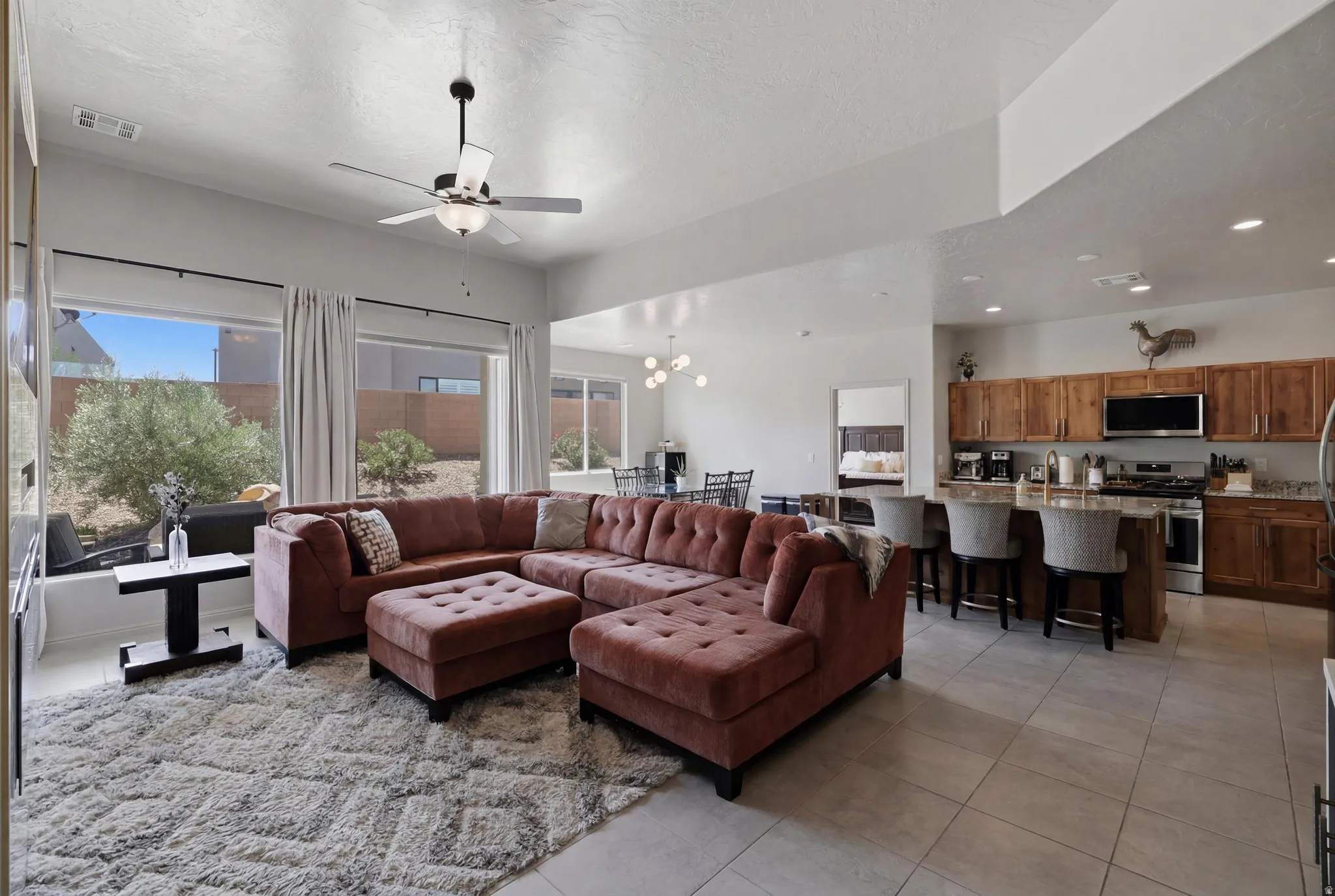 Open-concept living area featuring large windows, a ceiling fan, and tile flooring