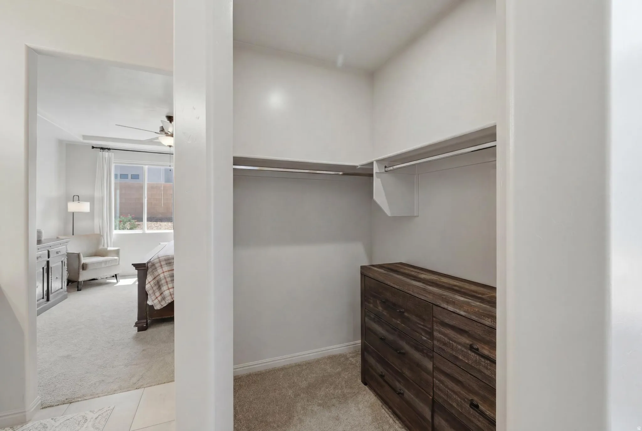 Walk-in closet featuring built-in shelving, hanging rods, and wood-finish drawer storage