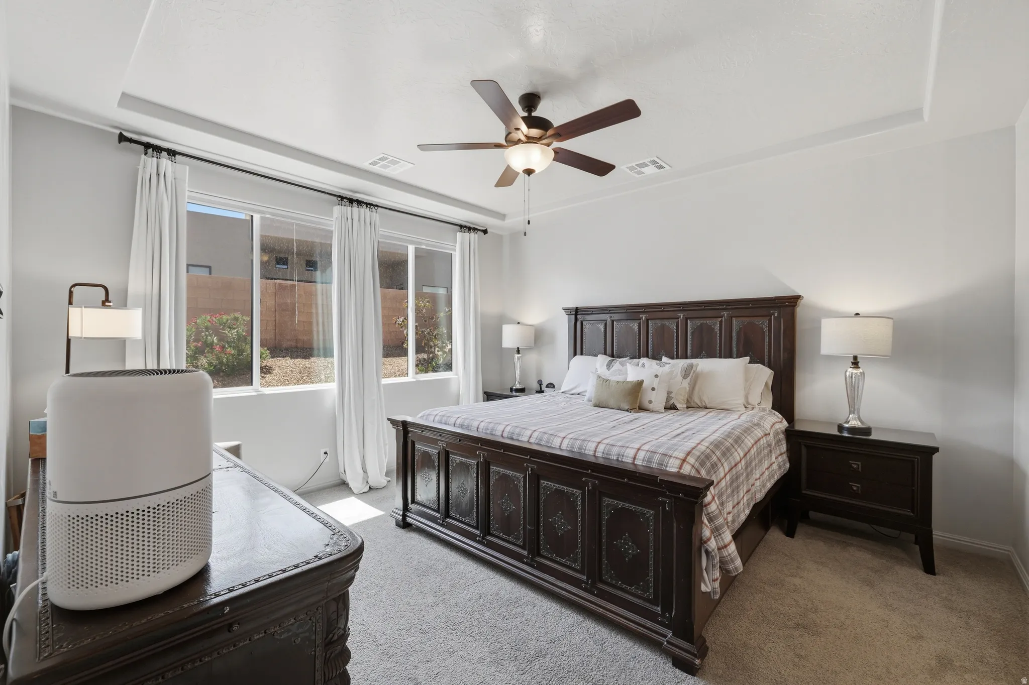 Spacious room featuring light gray walls, plush carpeting, and a tray ceiling