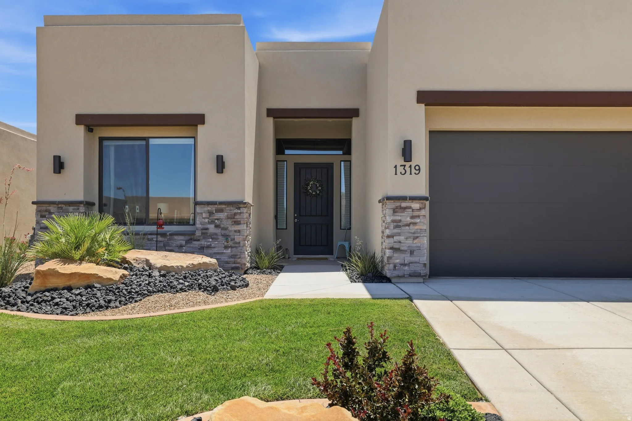 Contemporary stucco exterior featuring stone accents and a dark garage door