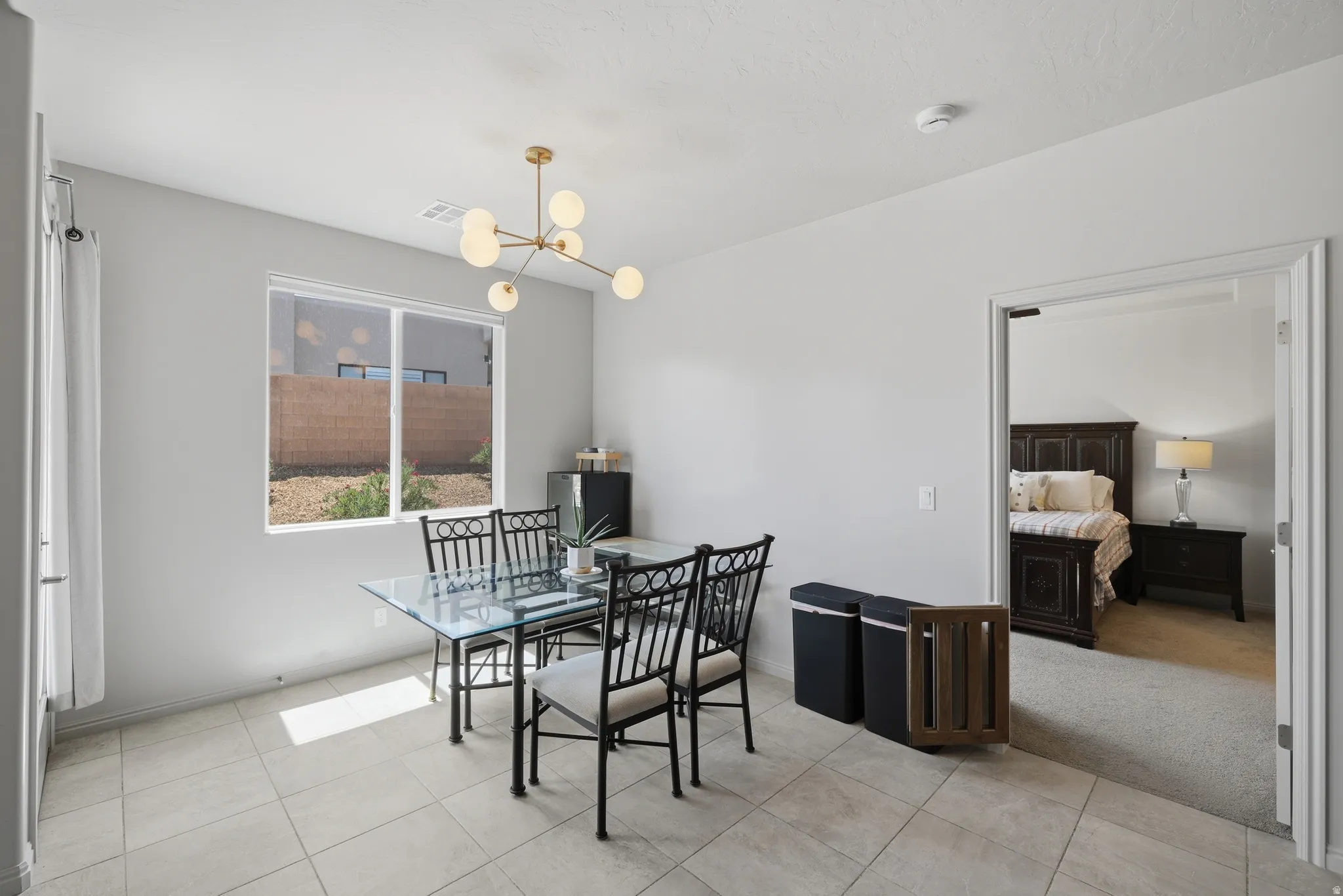 Dining area featuring a modern brass and glass chandelier, tiled flooring, and a large window