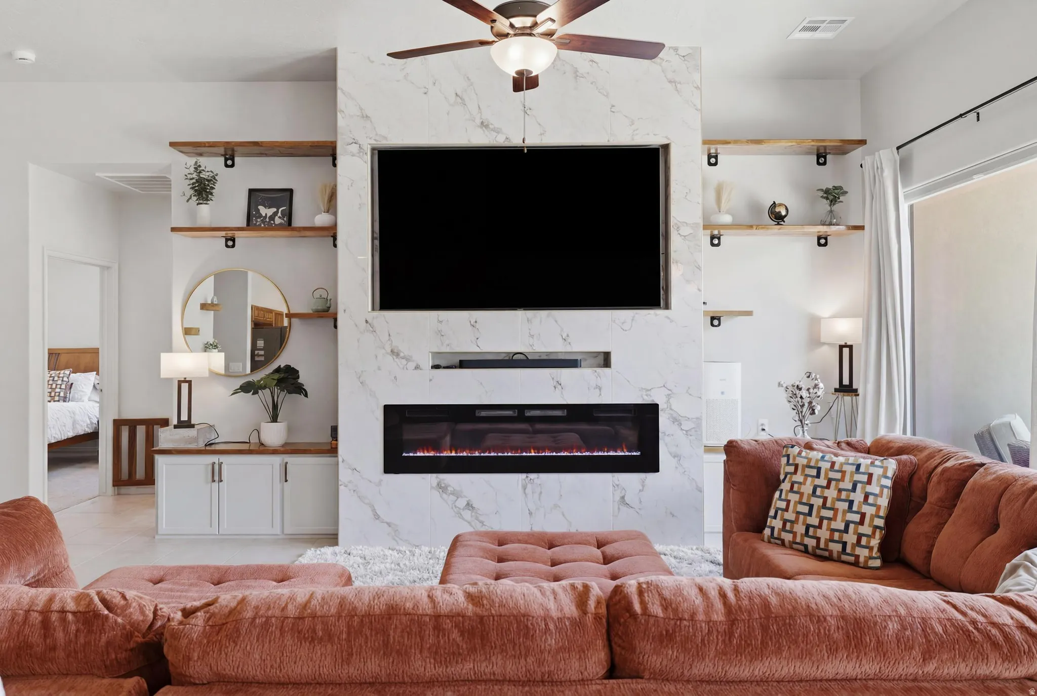 Contemporary living room featuring a floor-to-ceiling marble-look accent wall with an integrated electric fireplace
