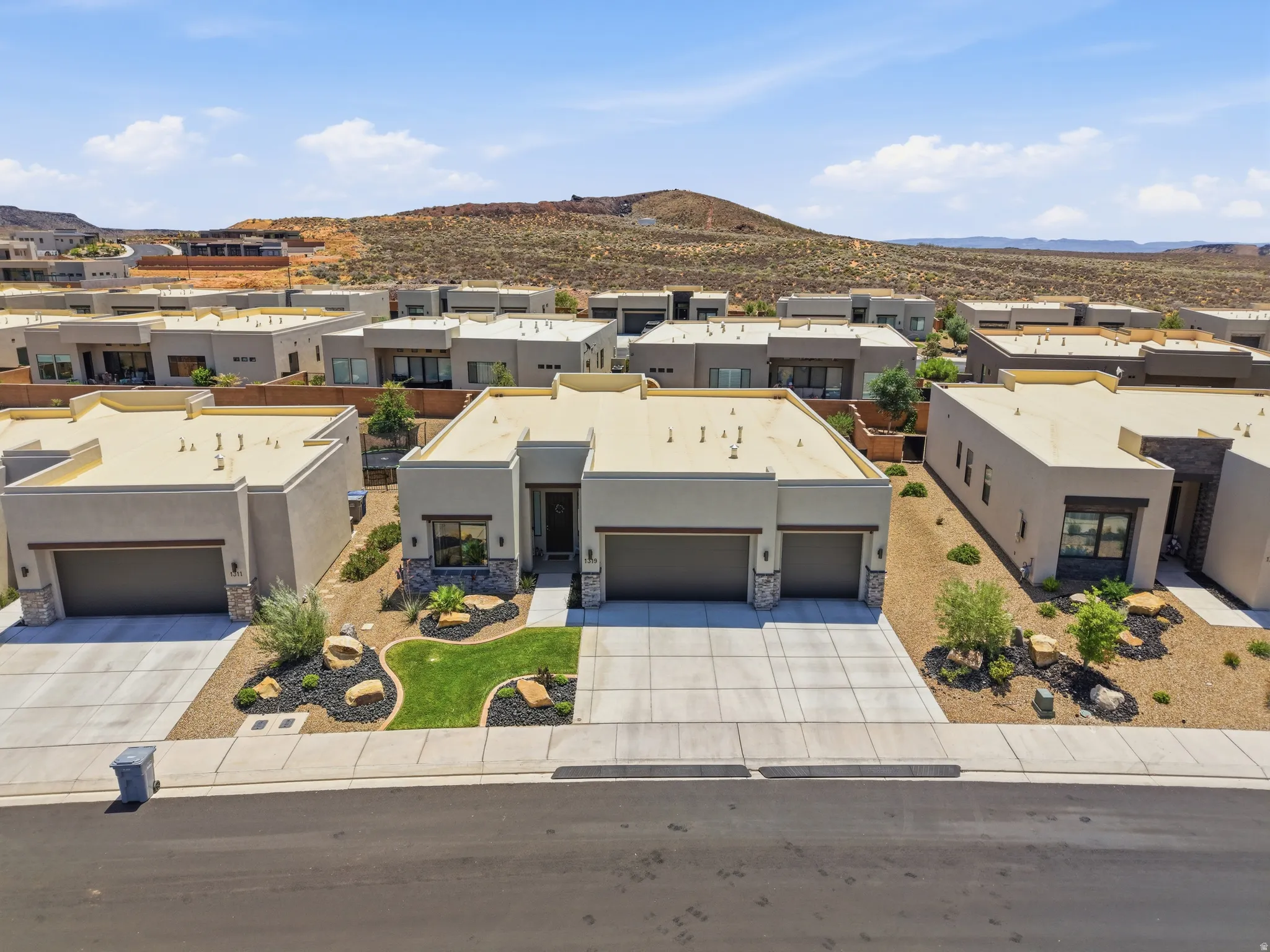 Contemporary stucco exterior featuring a stone accent wall and a two-car garage