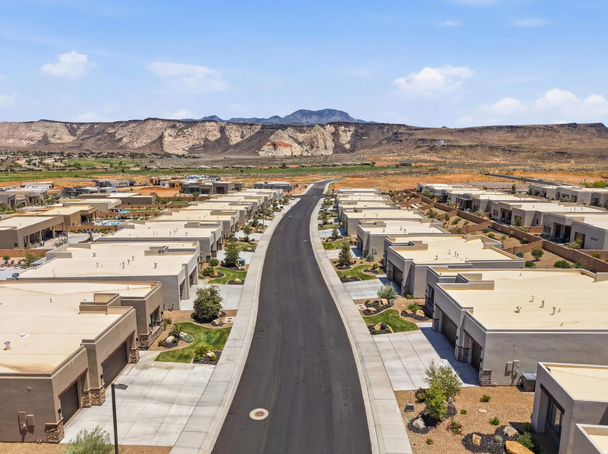 Modern desert community featuring a paved street, uniform architectural styles, and landscaped front yards