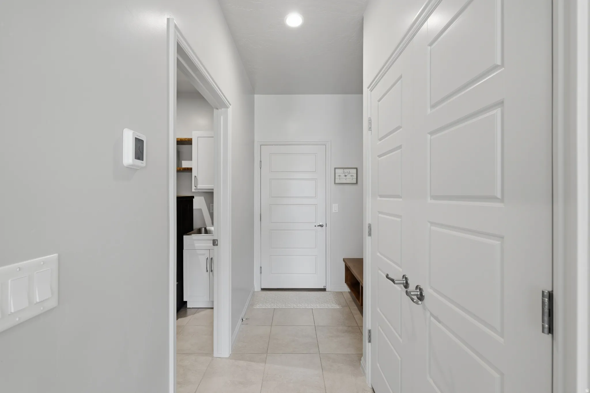 Hallway featuring neutral wall tones, recessed lighting, white trim, and tiled flooring