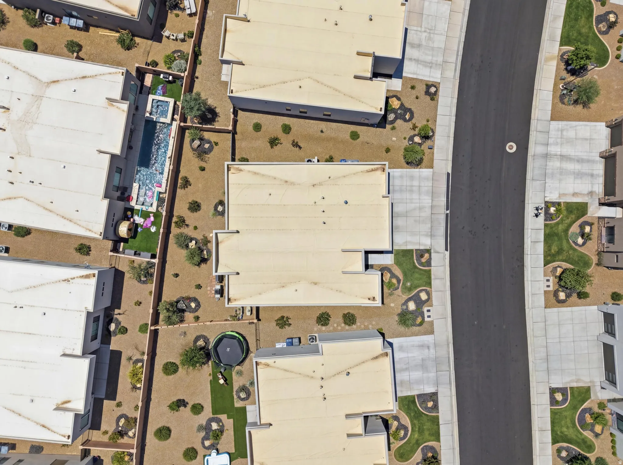 Aerial perspective of a modern residential property featuring a rectangular swimming pool with integrated spa and surrounding artificial turf