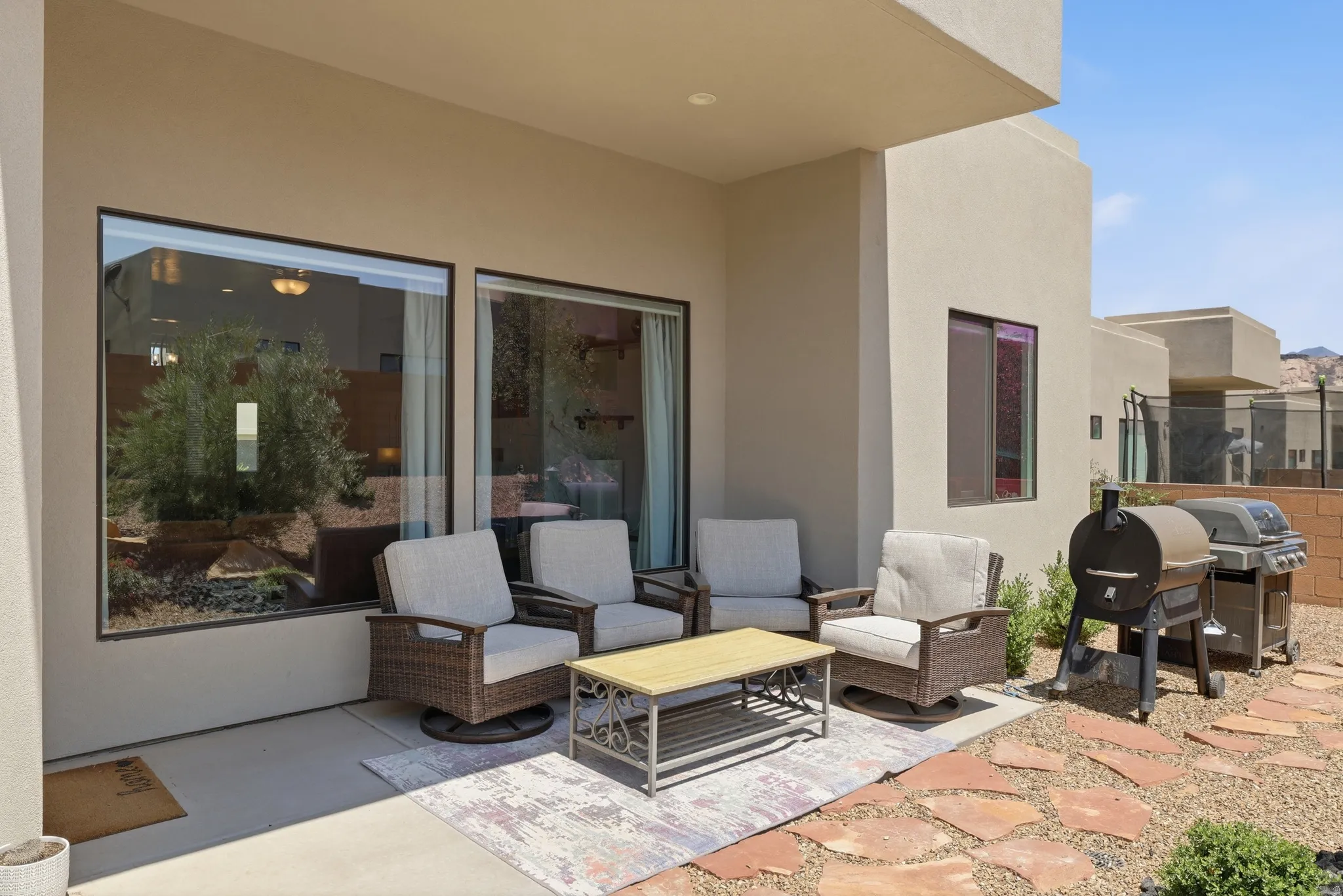 Covered patio with expansive windows, concrete flooring, and a flagstone pathway