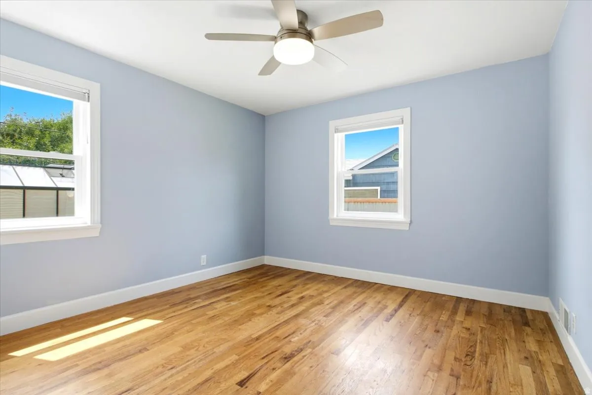 Room featuring natural wood-finish flooring, light blue wall paint, and white trim