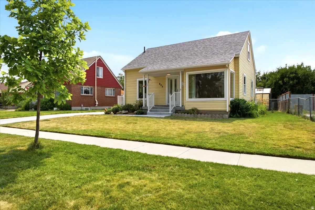 Charming light yellow siding exterior with a contrasting grey shingle roof