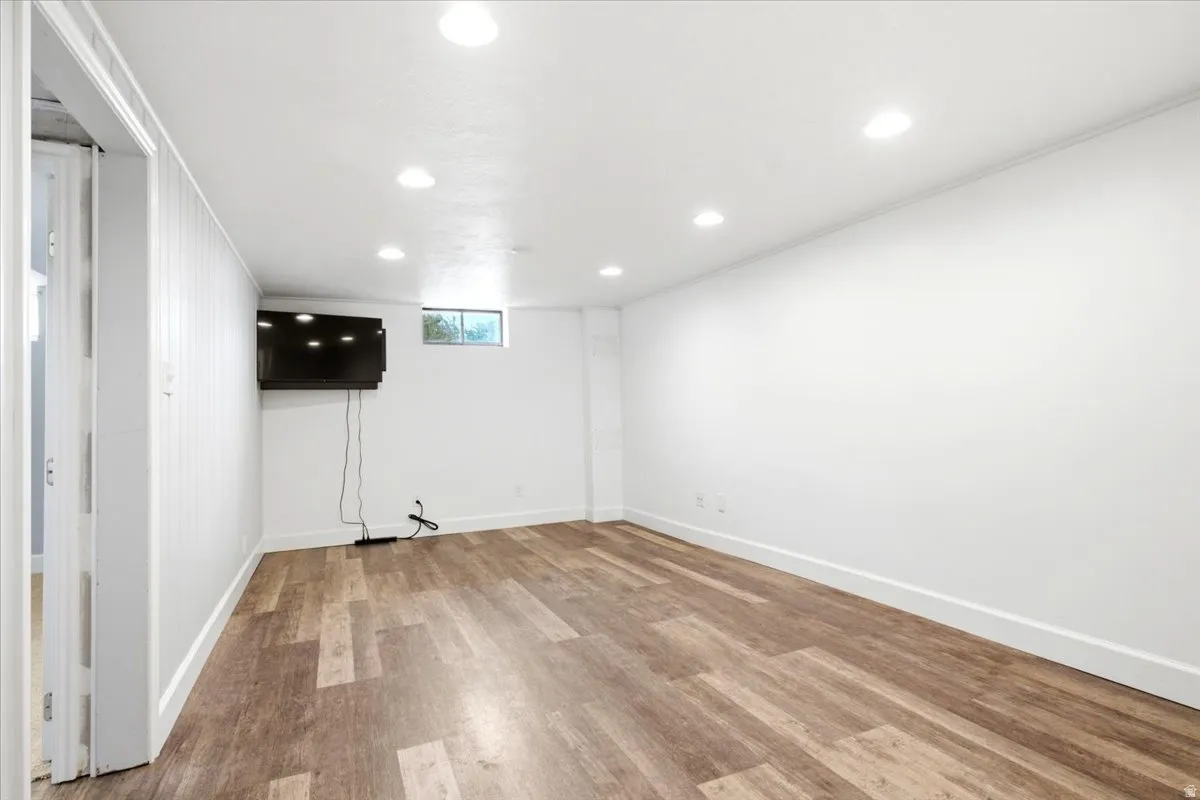 Spacious room featuring wood-finish flooring, recessed lighting, and a window