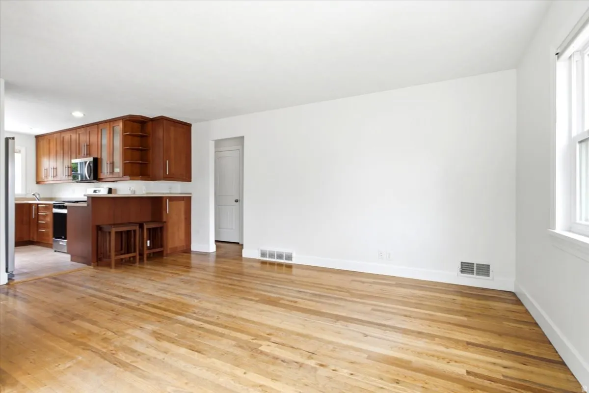 Open concept living area with wood-finish flooring, white walls, and a large window