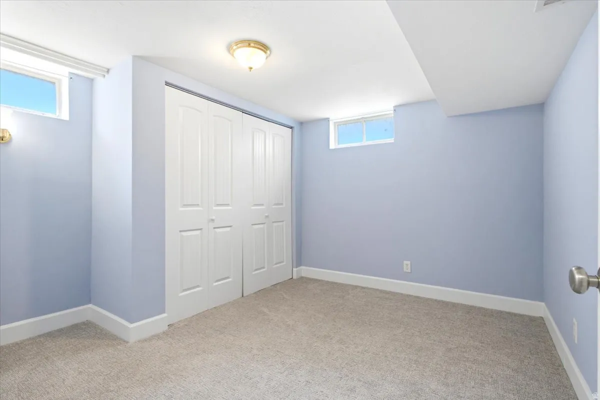 Interior room featuring light blue walls, light-colored carpet flooring, white baseboards, and two transom windows